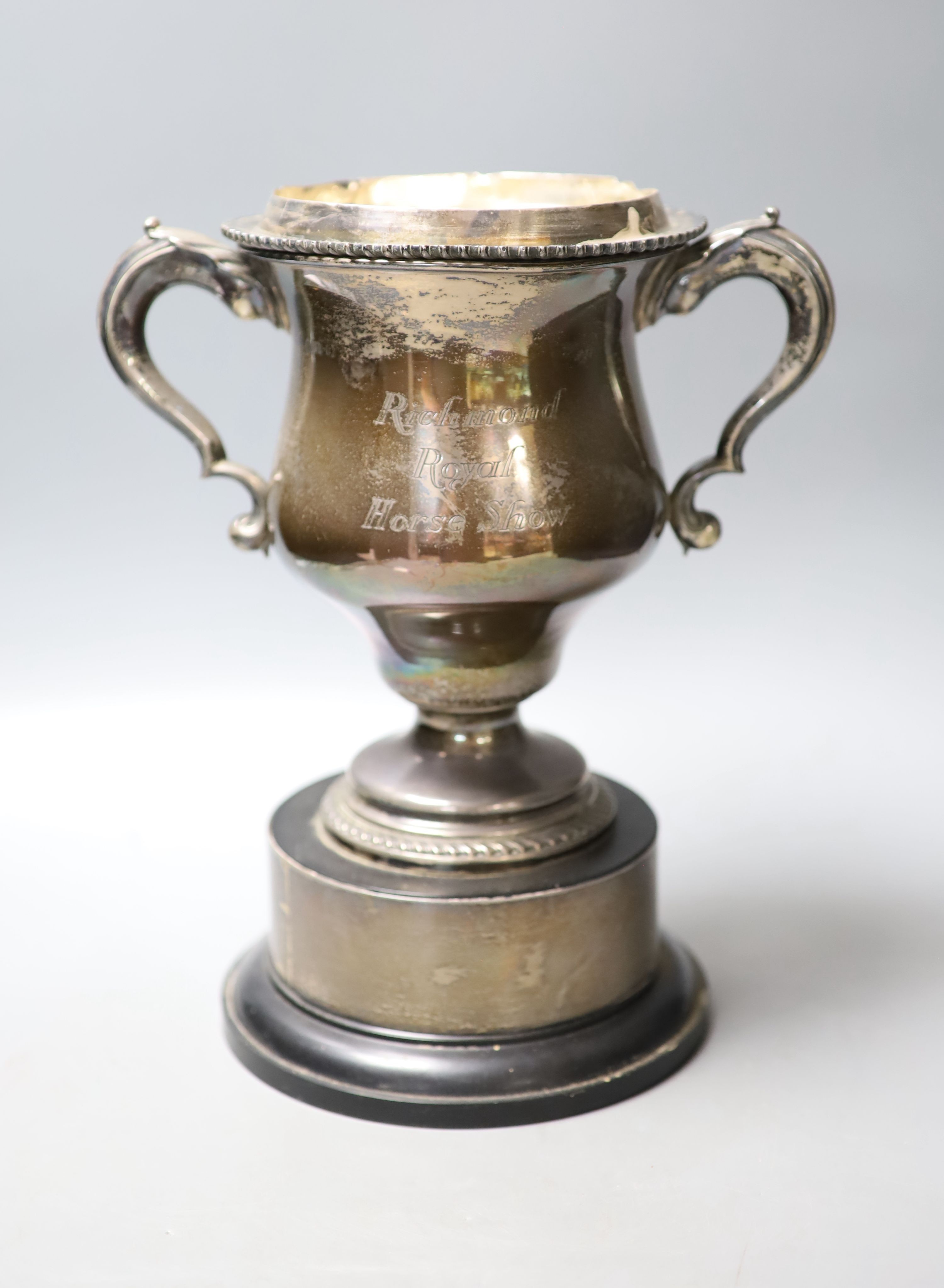 An Edwardian silver two handle presentation trophy cup and cover(a.f.) with later engraved inscription, Martin, Hall & Co, Sheffield, 1909, fixed to wooden socle, cup and cover height 30.4cm, cover 10.5oz.